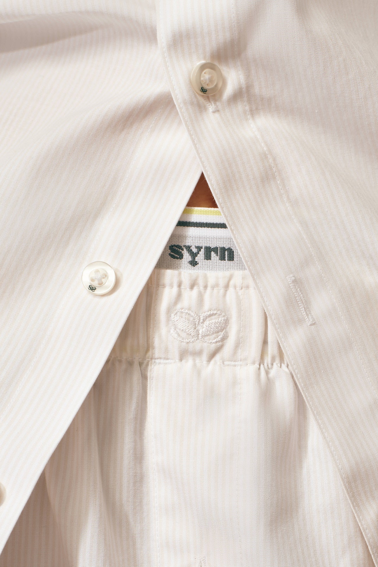 Close up of white striped button down and boxers with a SYRN waistband visible underneath/above the boxers