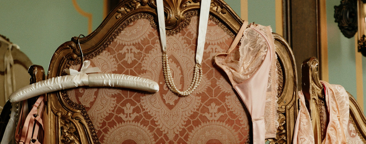 White hanger, jewelry, bra and underwear hanging over upholstered furniture